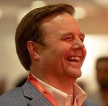 Attendee in a blazer laughing during a convention networking session